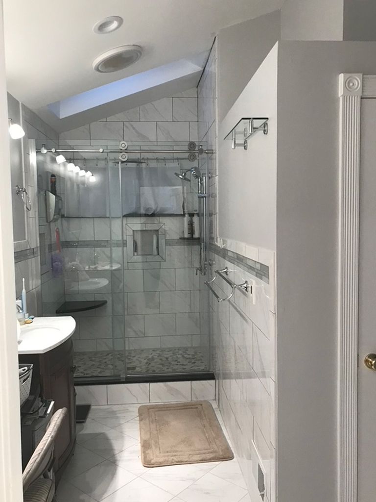 A bathroom with a walk in shower , sink , and toilet.