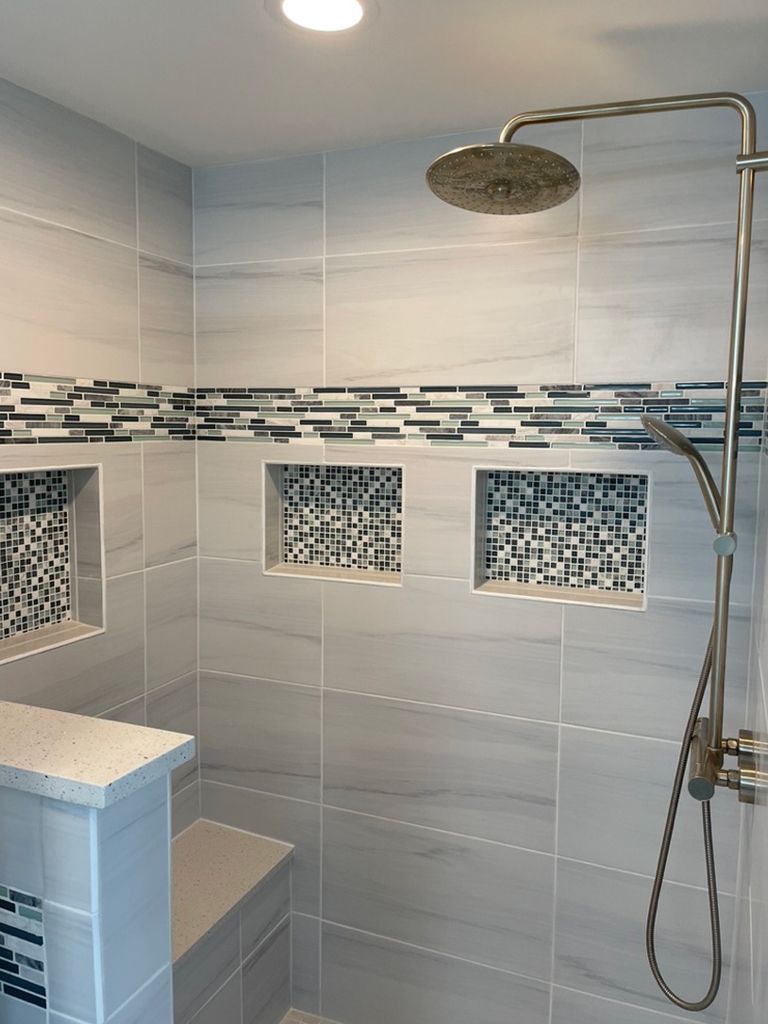 A shower with a shower head and a bench in it.