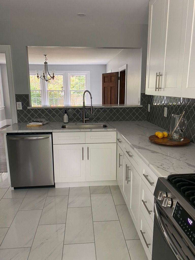 A kitchen with white cabinets , a stove , a sink , and a dishwasher.