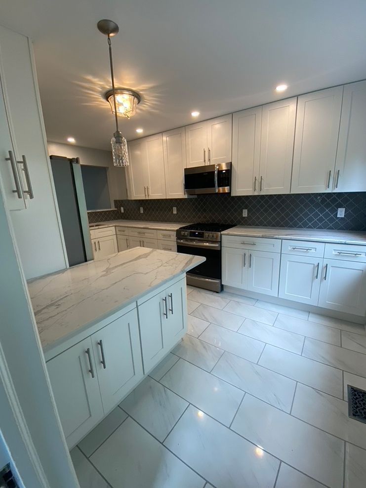 A kitchen with white cabinets , stainless steel appliances , and a large island.