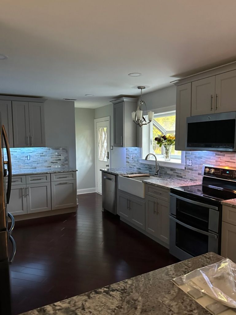 A kitchen with white cabinets , granite counter tops , stainless steel appliances and a sink.