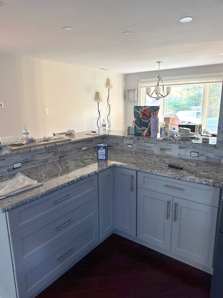 A kitchen with granite counter tops and white cabinets.