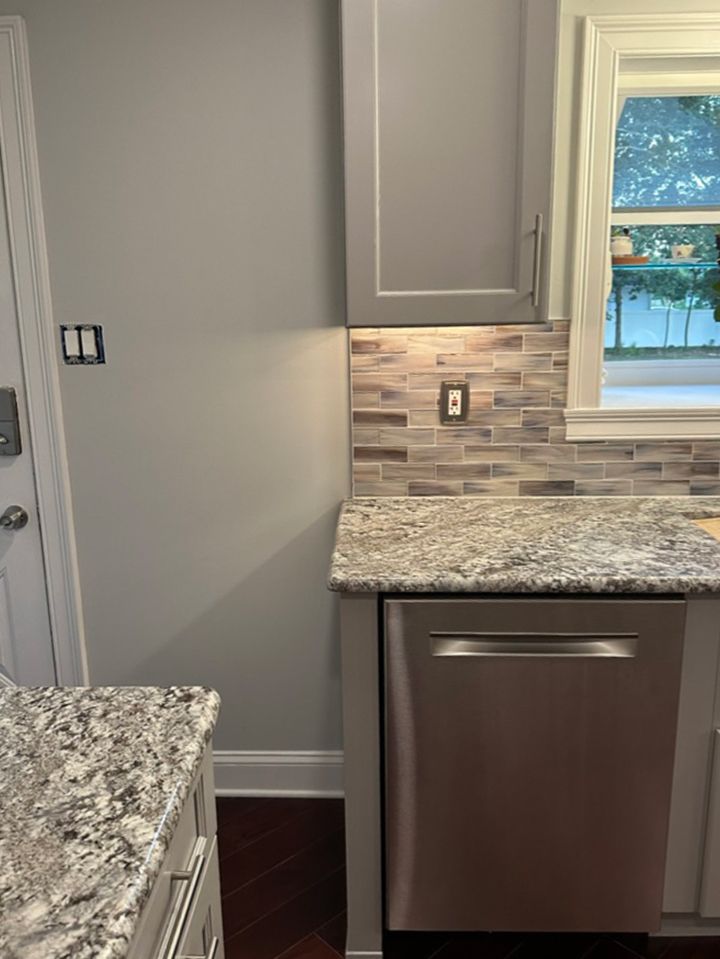A kitchen with granite counter tops and a stainless steel dishwasher.