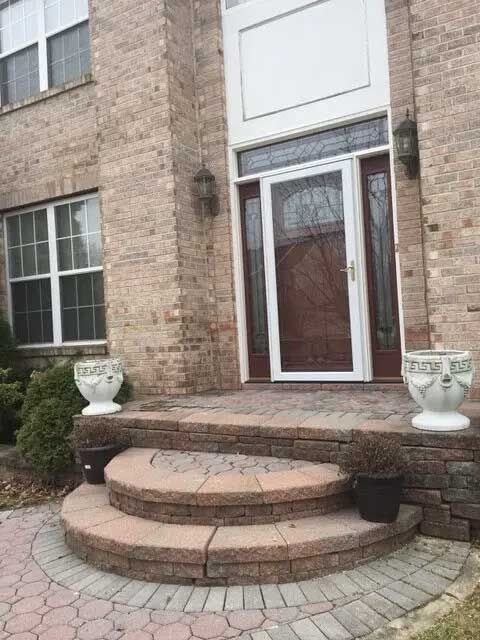 A brick house with a porch and steps leading to the front door.
