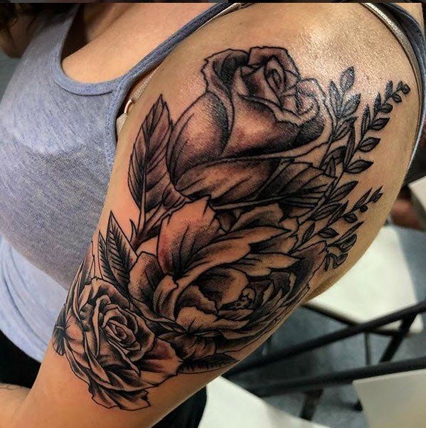 Black and white rose tattoo on a woman's upper arm.