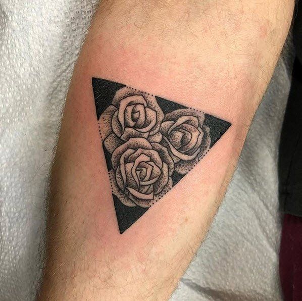 Black triangle tattoo with three roses on an arm.