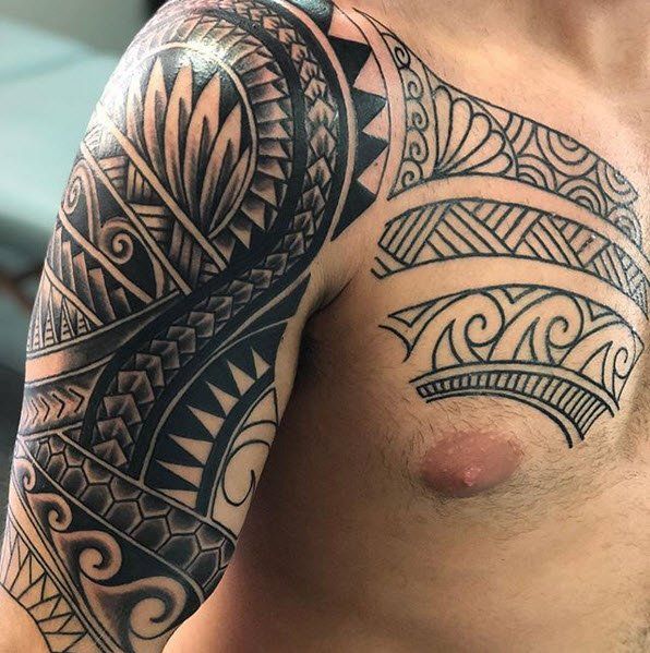 Tattoo on a man's arm and chest, featuring Polynesian tribal patterns in black ink.