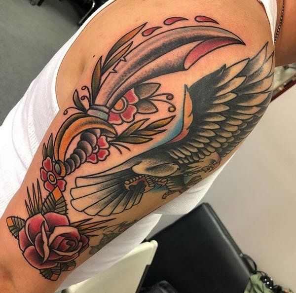 Tattoo on arm: eagle with spread wings, sword, and roses in traditional style.
