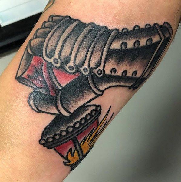 Tattoo of a metal gauntlet holding a burning lantern, black and gray with red and yellow flames.