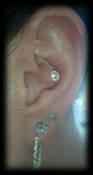 Ear with multiple silver earrings.