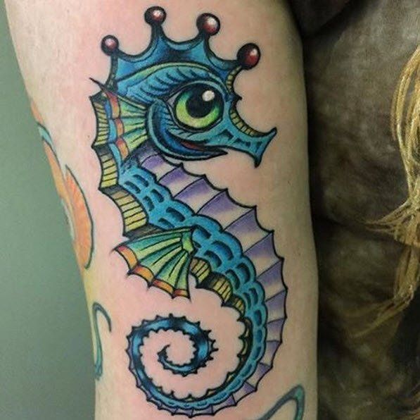 Colorful seahorse tattoo with a crown on arm.