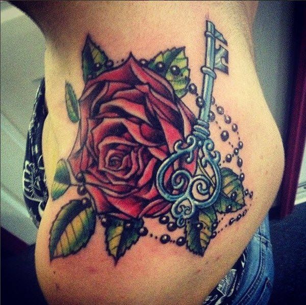 Rose tattoo with key and beads on skin. Red, green, and blue colors.