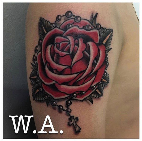 Tattoo of a red rose and rosary on a person's arm.