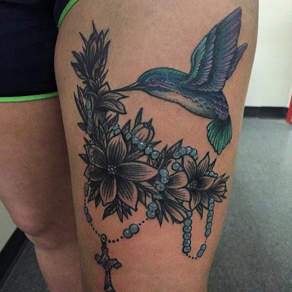 Hummingbird tattoo with flowers, blue rosary on thigh.