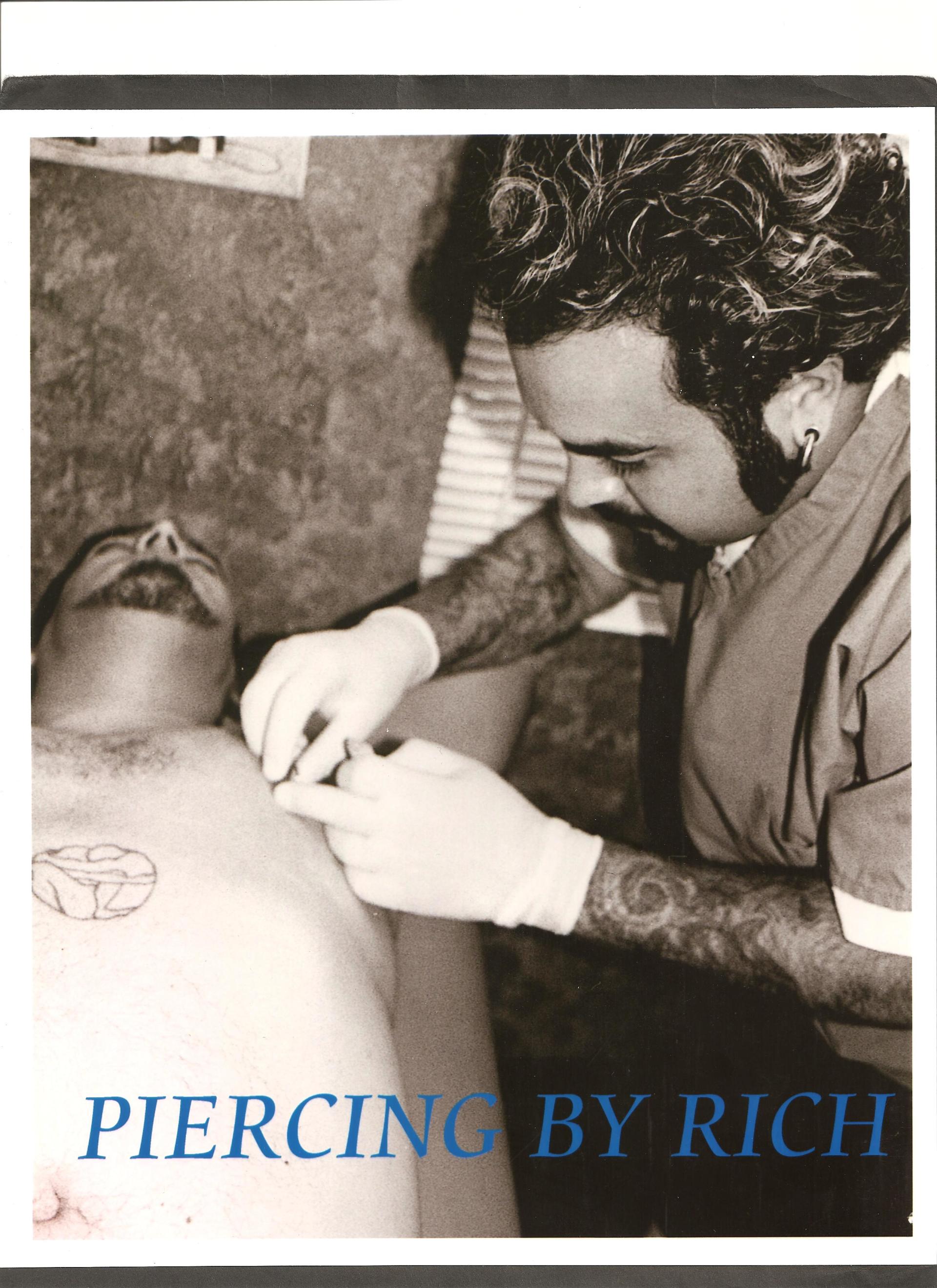 Man getting a chest piercing. Piercer wearing gloves, working on client in studio.