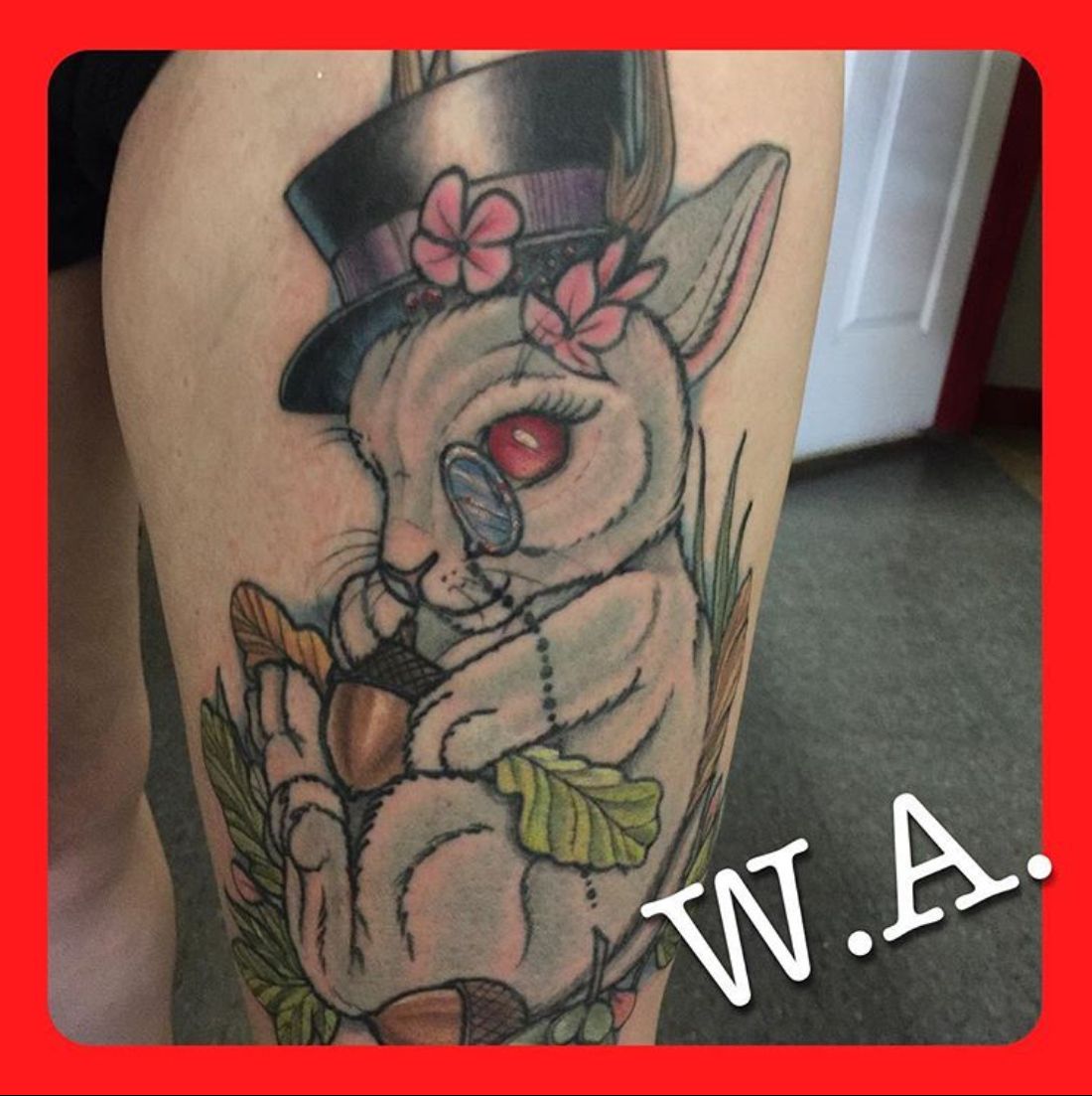 Tattoo of a bunny wearing a top hat, holding an acorn, and looking through a monocle; colorful on leg.