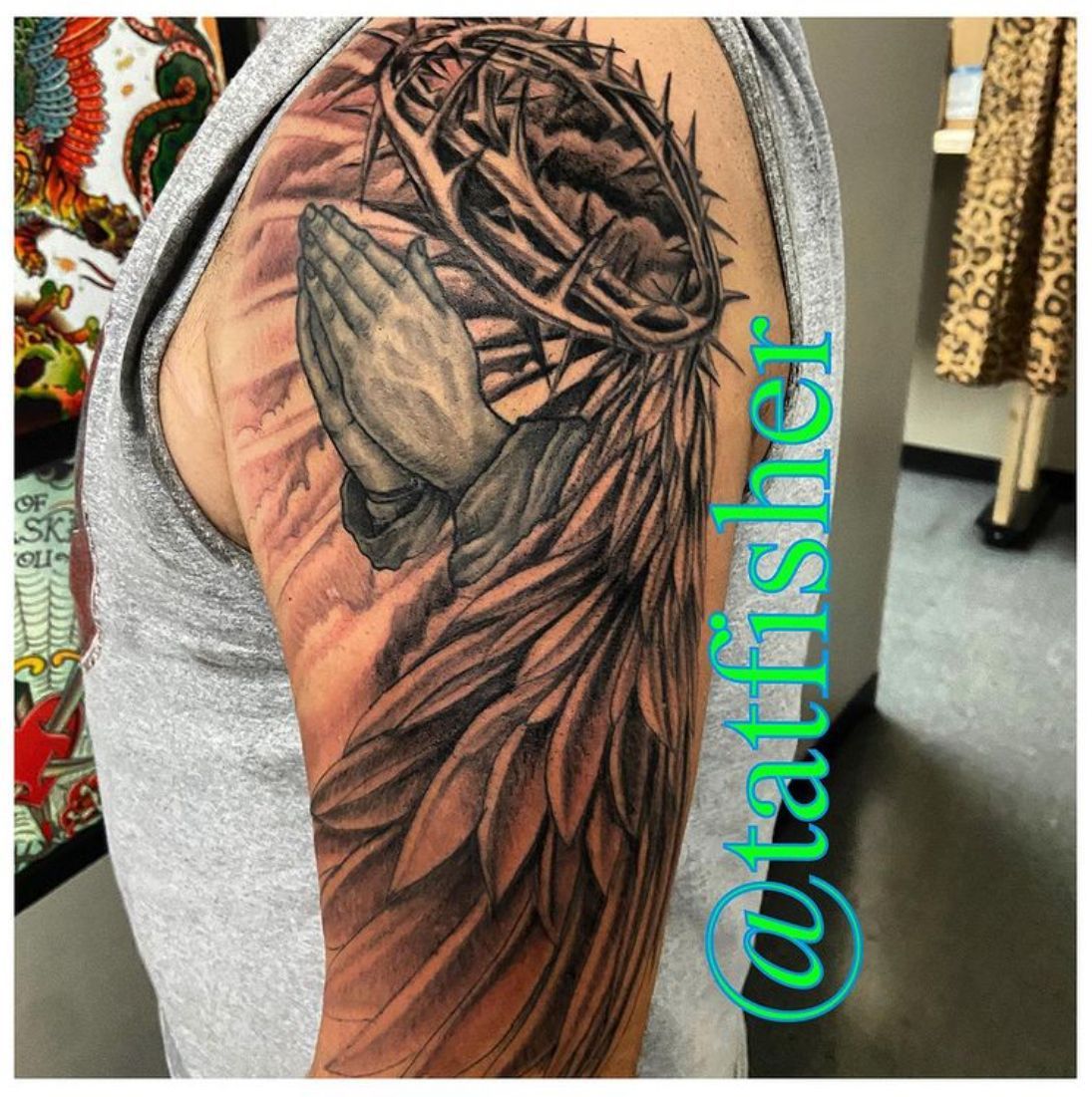 Tattoo of praying hands, a crown of thorns, and an angel wing on an arm.