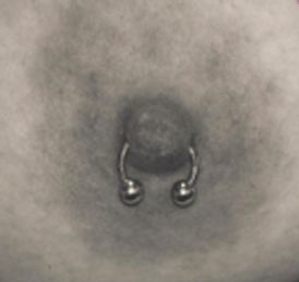 Close-up of a nipple with a silver horseshoe barbell piercing.