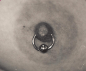 Close-up of a nipple with a silver barbell piercing. The areola is a darker shade.