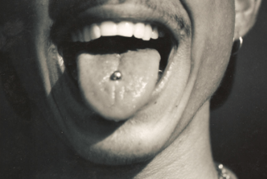 Close-up of person smiling, tongue pierced with a silver stud.
