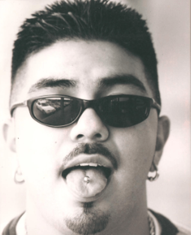 Man with tongue piercing, sunglasses, and goatee.