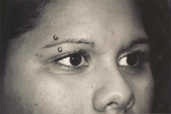 Close-up of a person with eyebrow piercings.