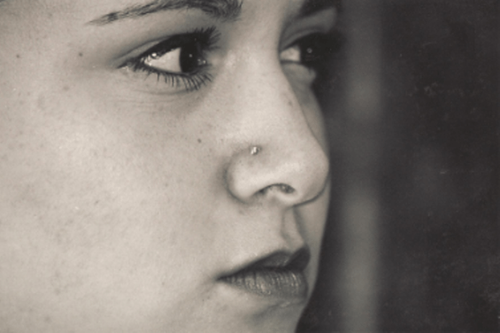 Black and white portrait of a young woman looking away with a nose stud.