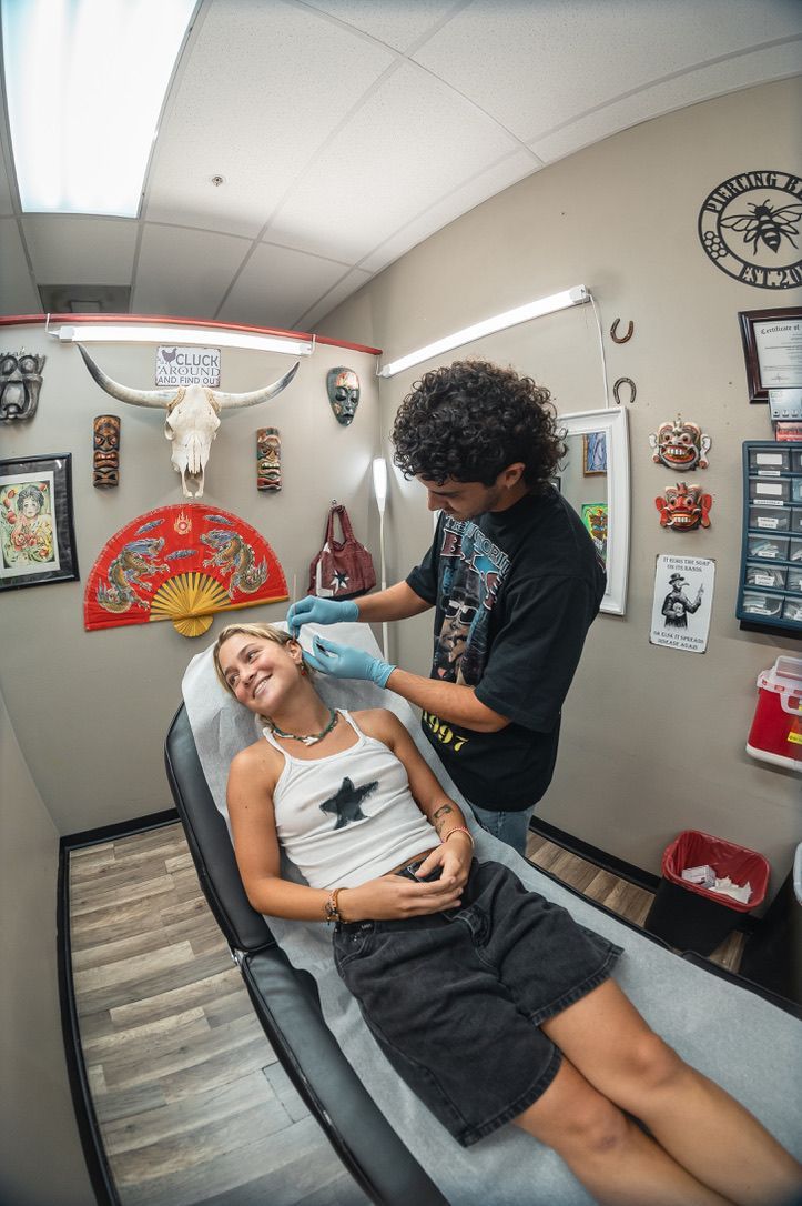 Person getting ear pierced by piercer in shop.