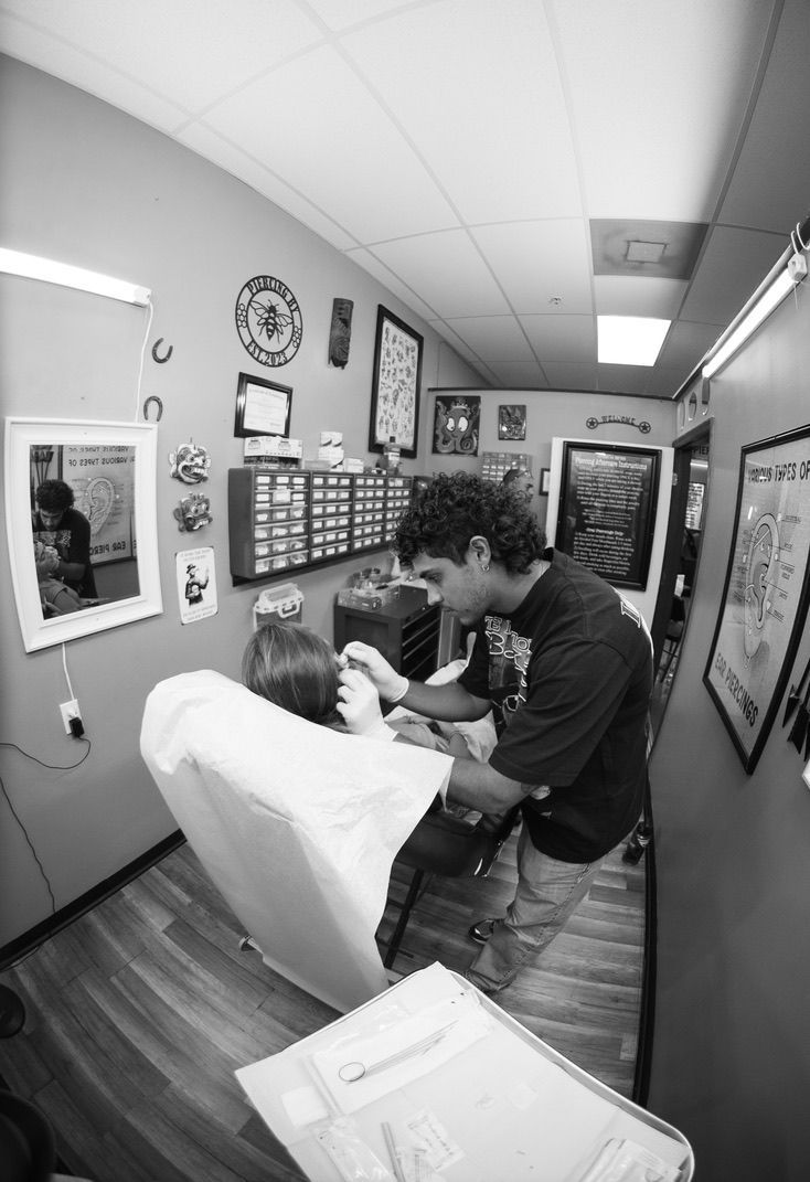 Black and white photo of a barber cutting a client's hair in a small shop.