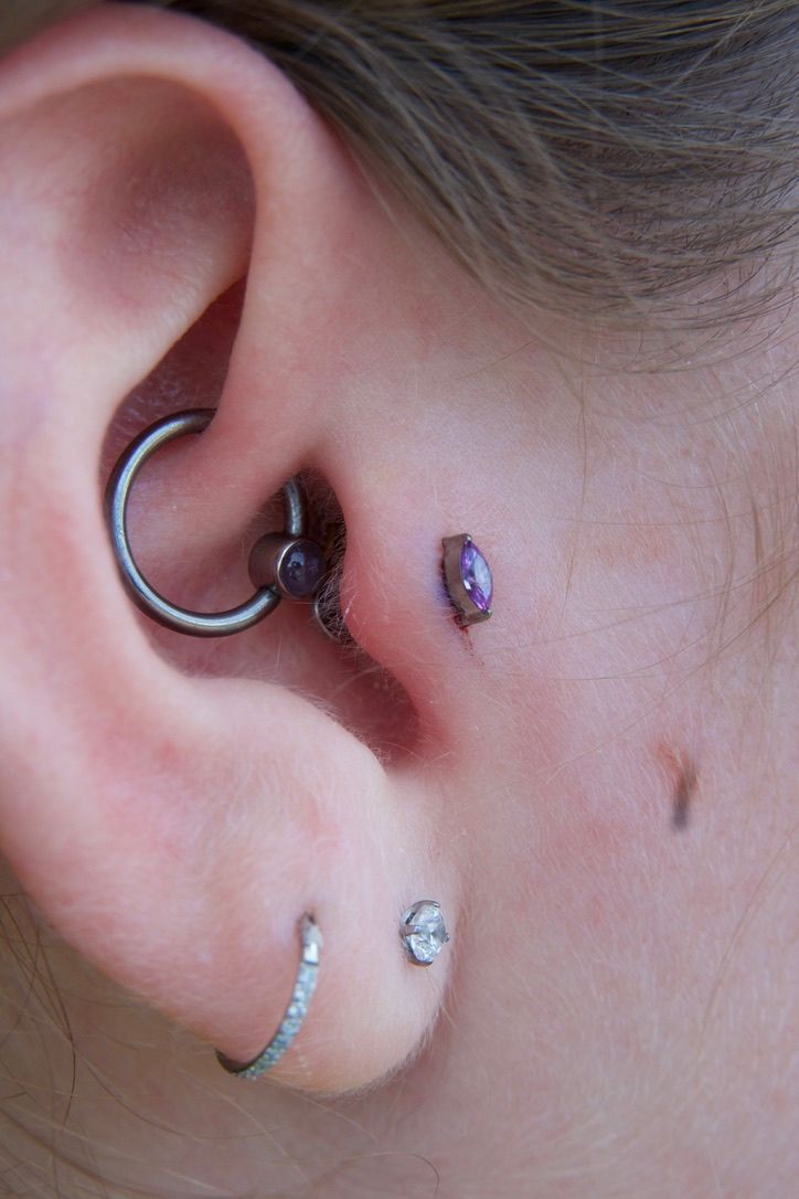 Ear with multiple piercings, including a hoop, studs, and a bar.