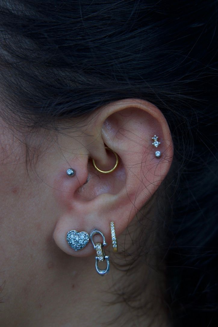Ear with multiple piercings, including hoops, studs, and dangling earrings.