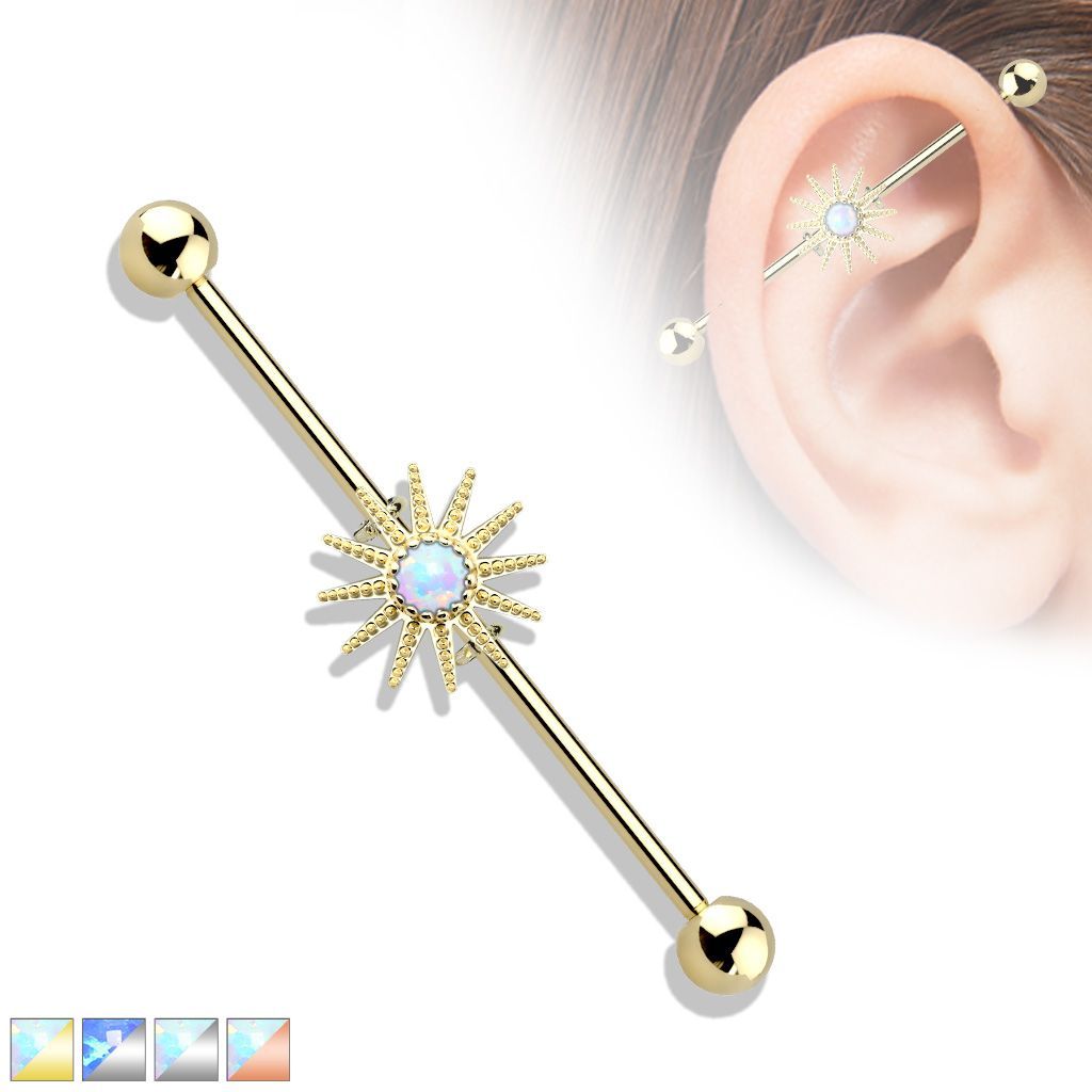 Gold industrial barbell piercing with sunburst and opal center.