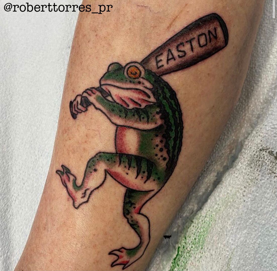 Tattoo of a green frog playing baseball. It swings a bat that says Easton.