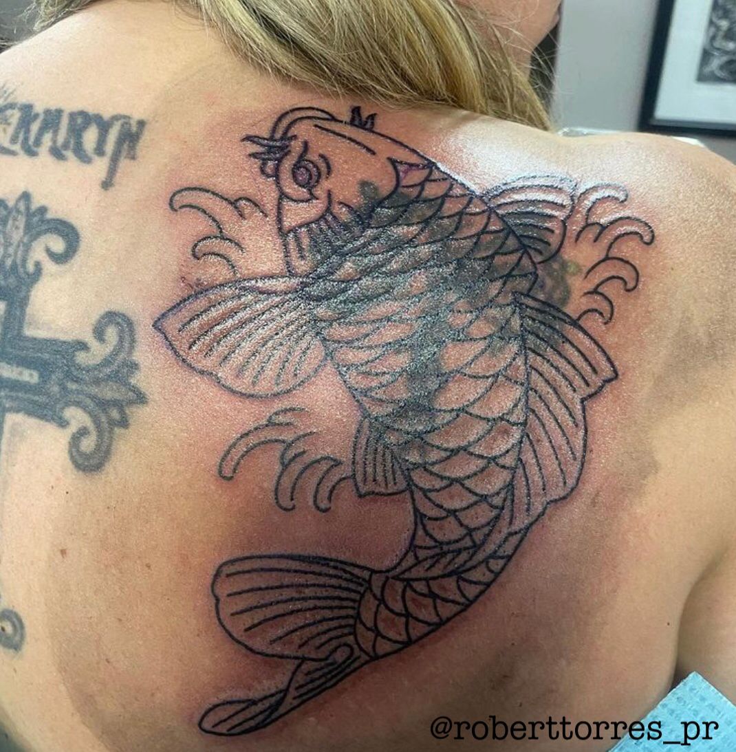 Back tattoo of a koi fish in black ink; woman's upper back.