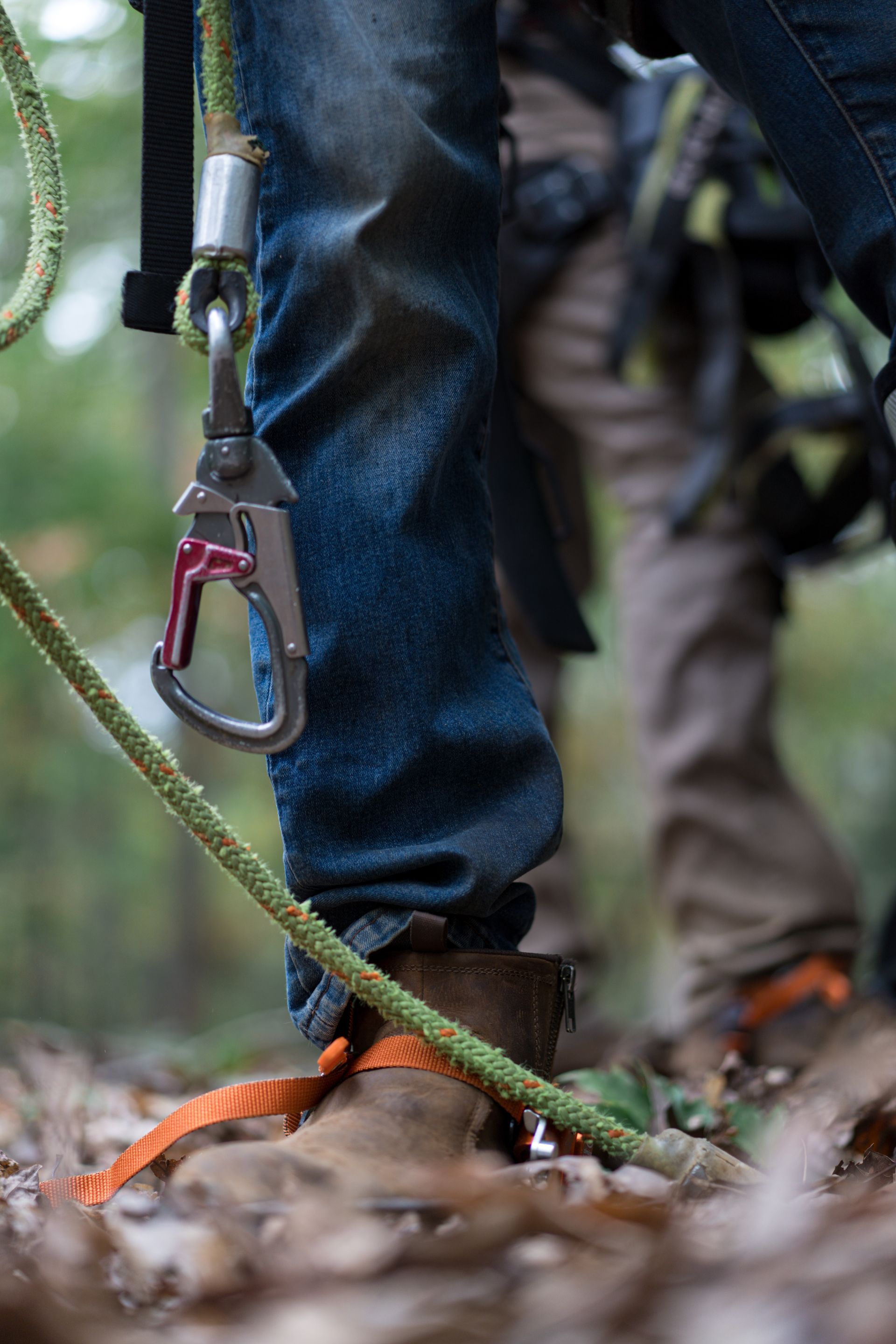 Climber’s foot on a rope bridge, with a carabiner clipped to a rope in a forest setting