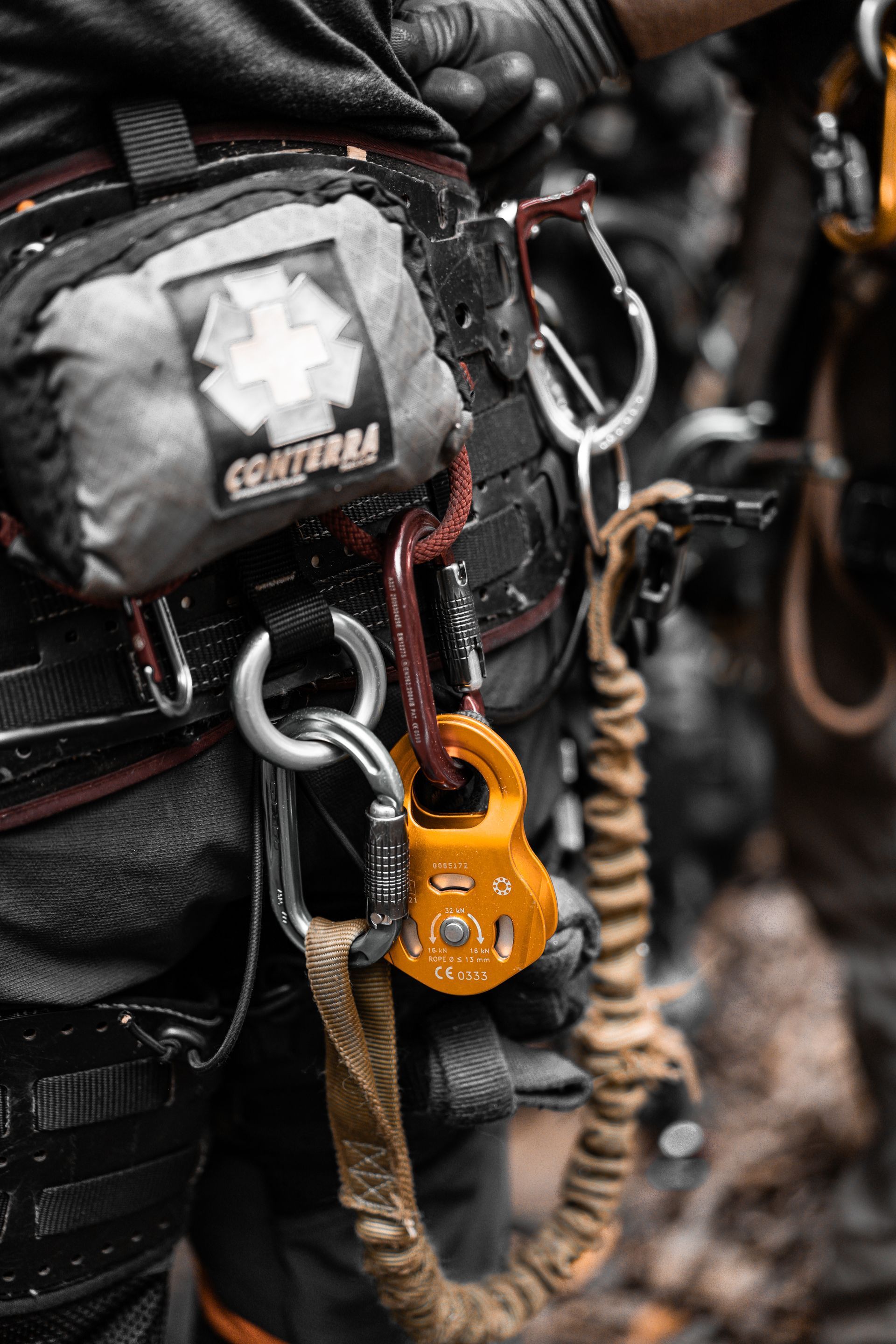 Close-up of climbing gear with orange belay device clipped to a rope on a harness