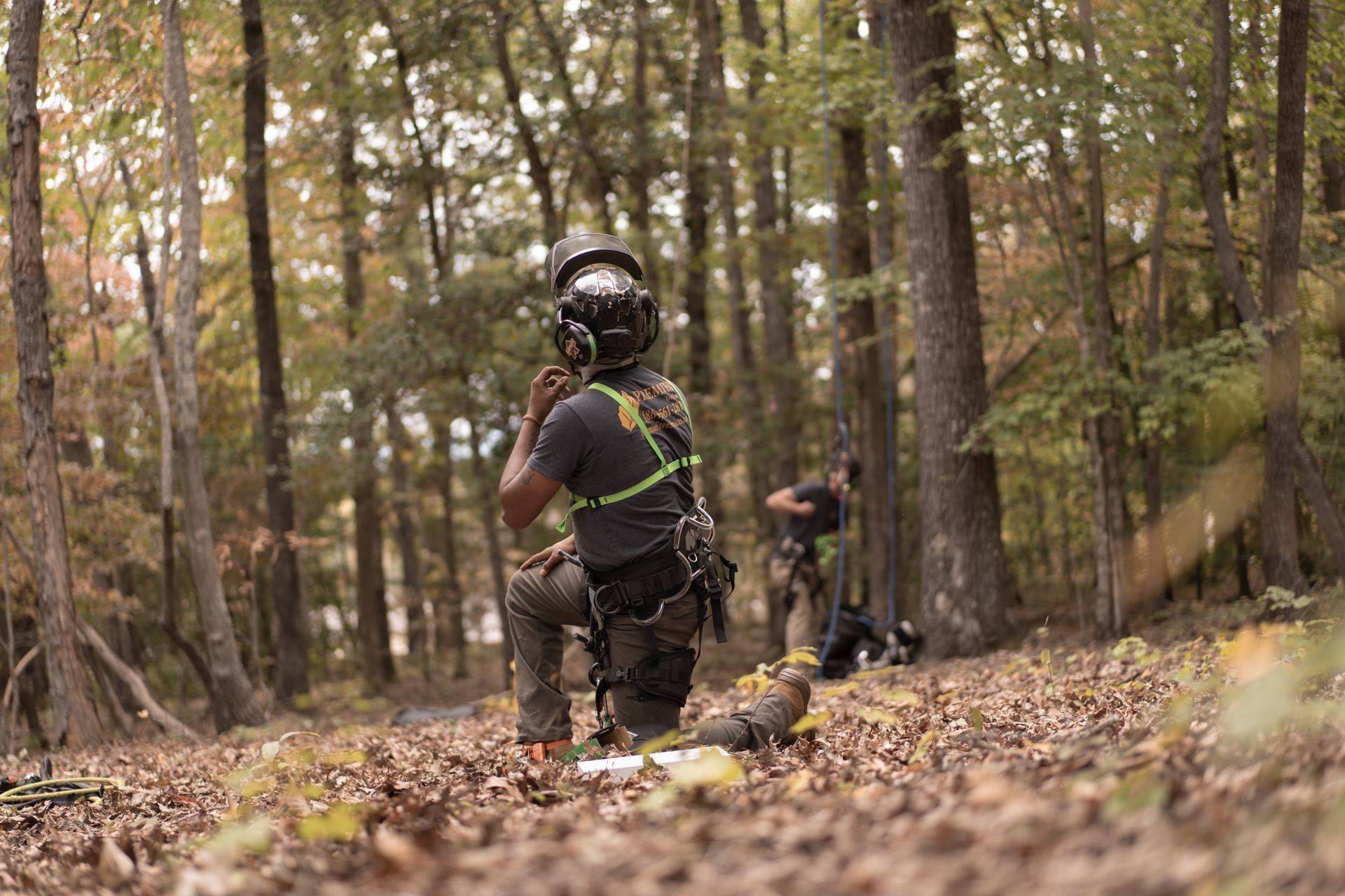 Children in helmets ride small bikes on a leaf-covered forest trail
