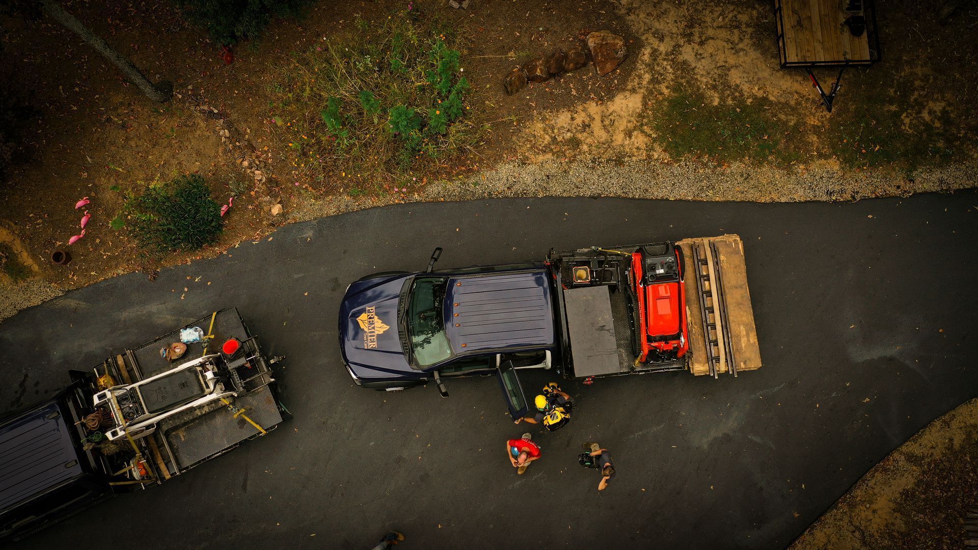 Overhead view of two off-road vehicles on a wet road beside muddy terrain, with people nearby.