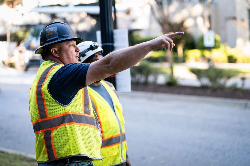 Construction worker in yellow safety vest and hard hat pointing down a road