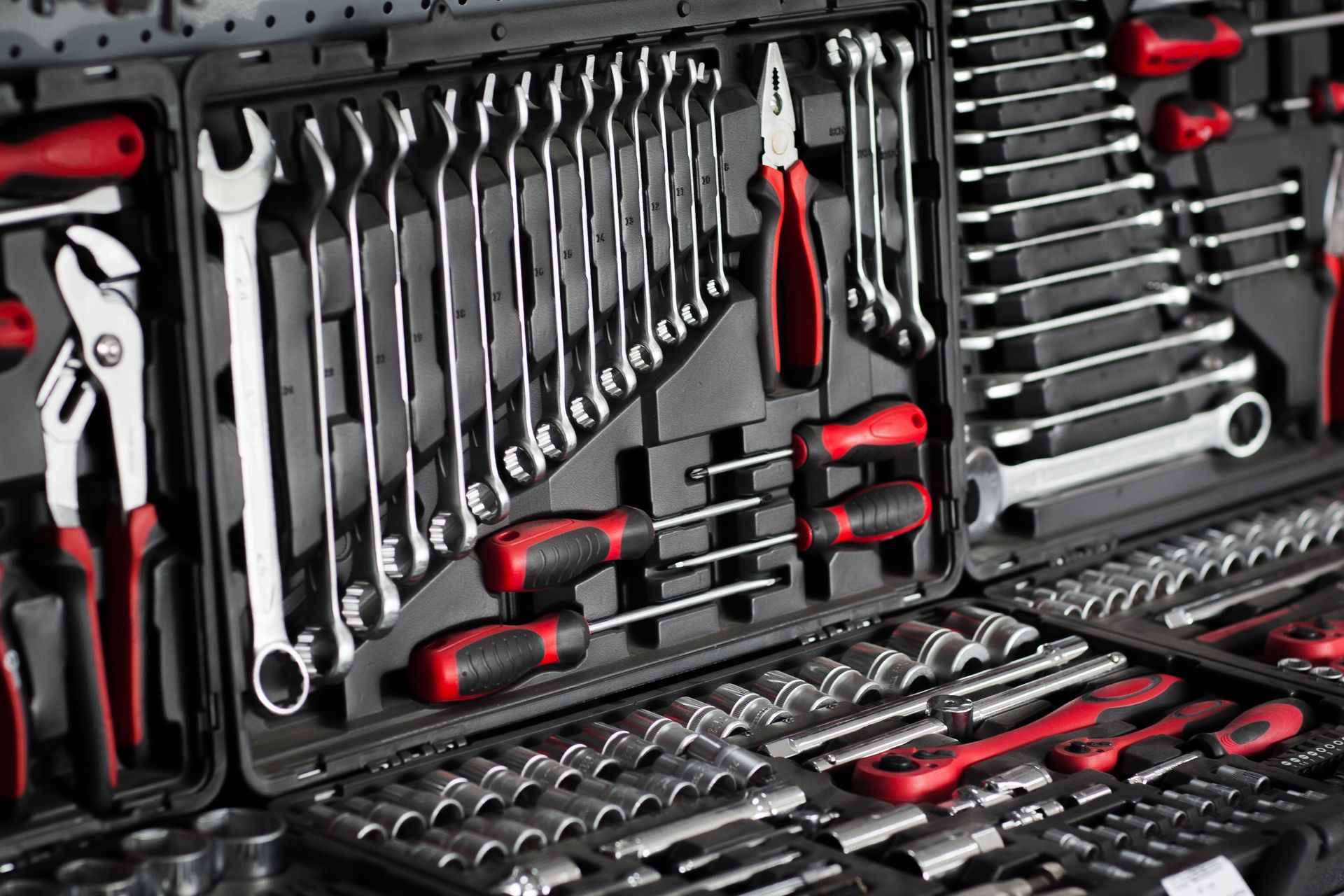 Open toolbox filled with a variety of tools, including wrenches, screwdrivers, and sockets; red and black handles.