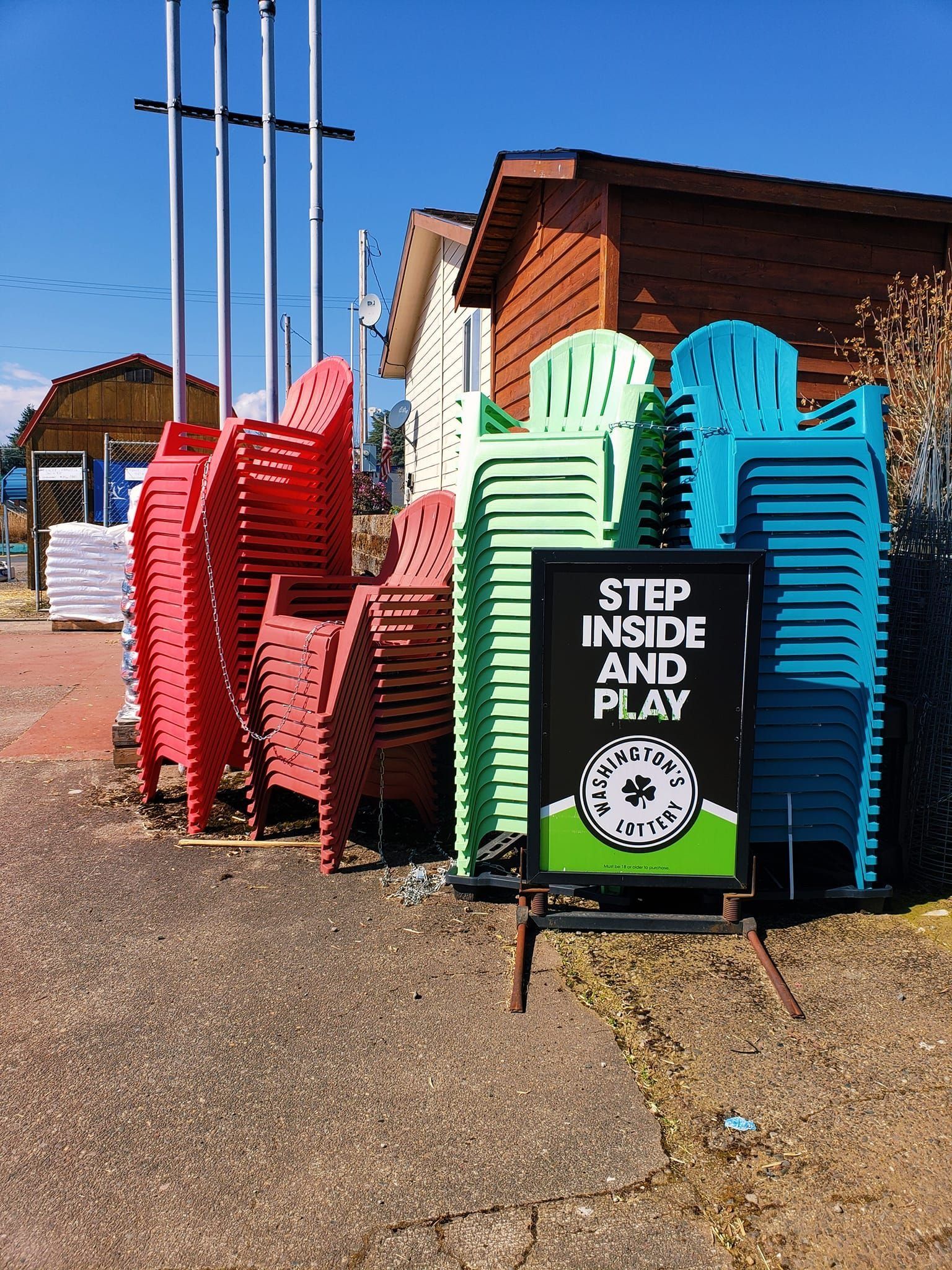 Stacks of red, green, and blue chairs beside a sign that reads 