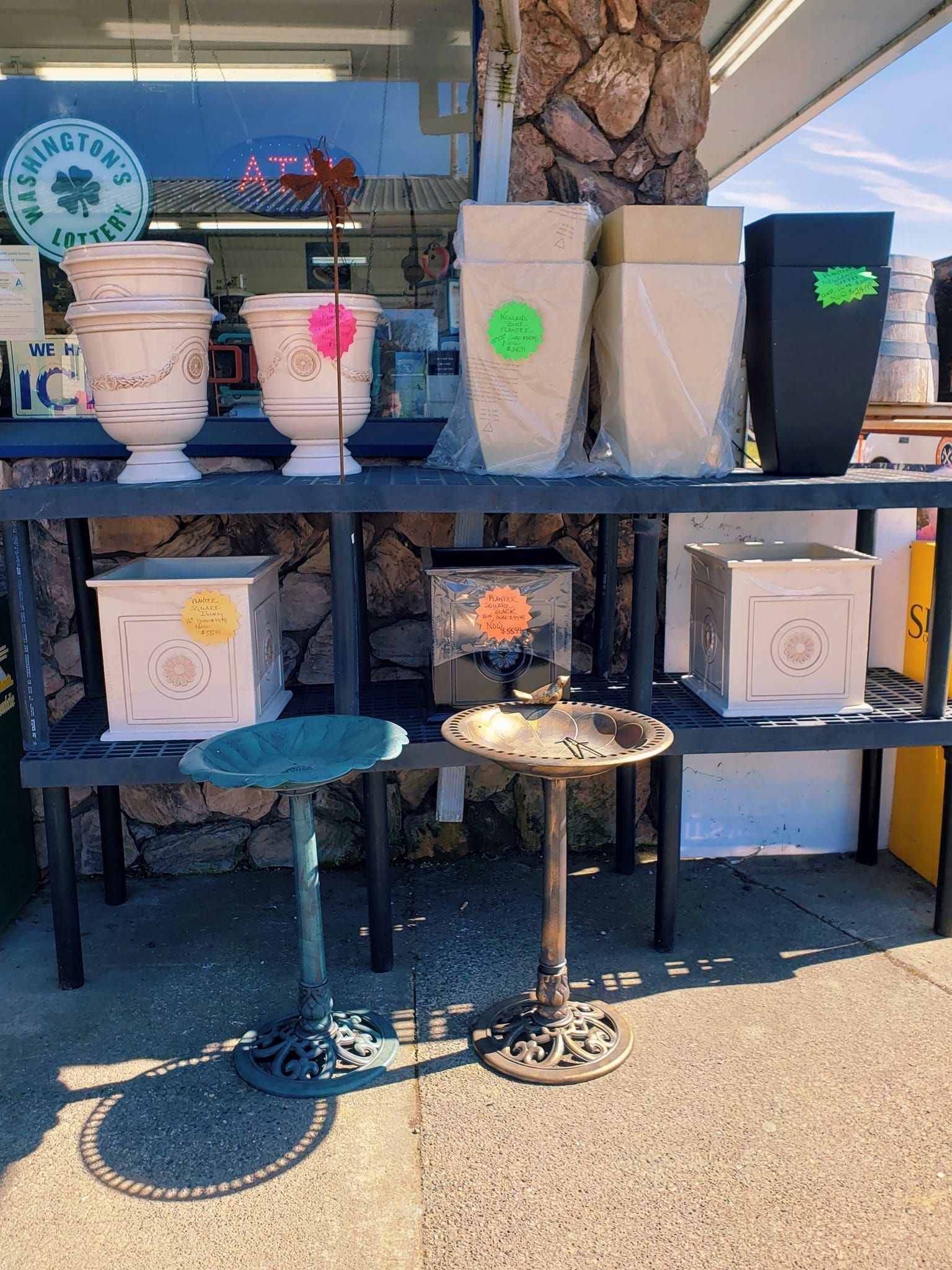 Planters and bird baths on display at an outdoor shop.