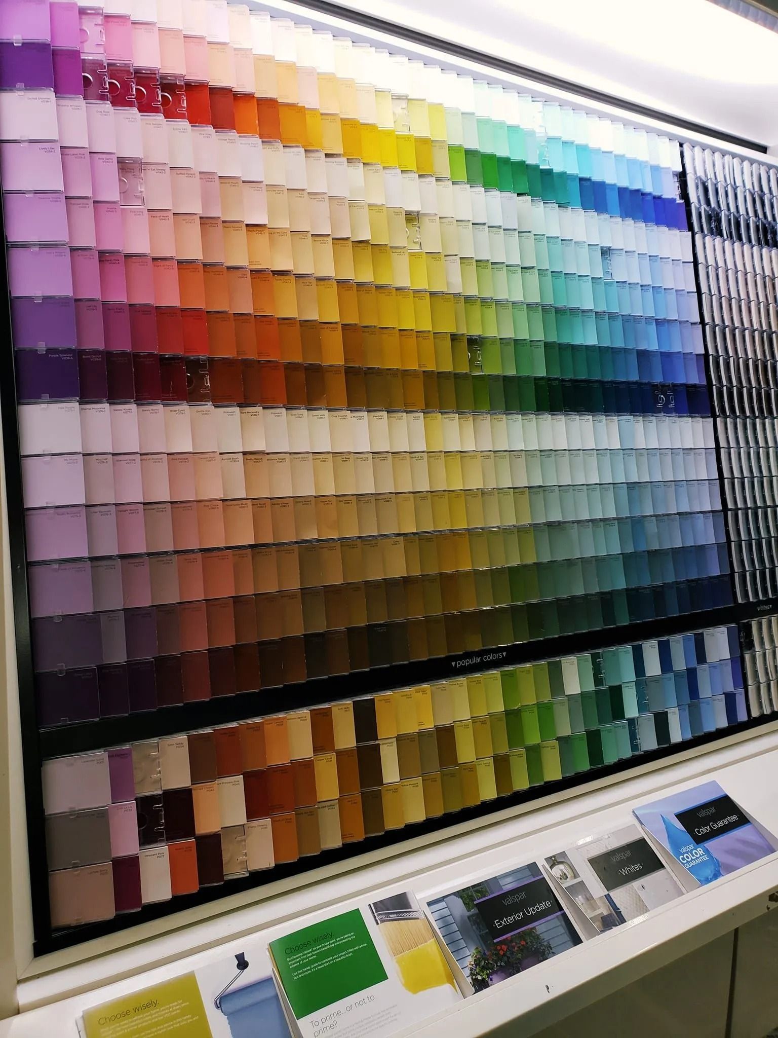 Paint color samples arranged in a rainbow gradient on a display in a store.