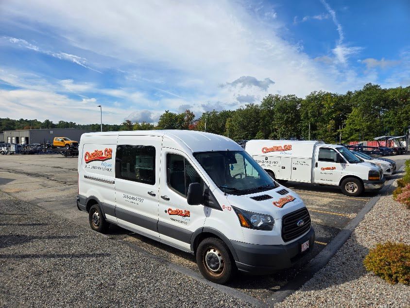 White company vans parked outside on a sunny day. The vans have orange lettering.