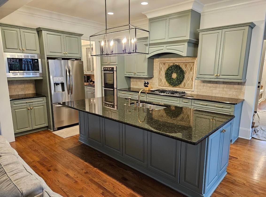 Modern kitchen with gray cabinets, granite island, stainless steel appliances, and wood floors