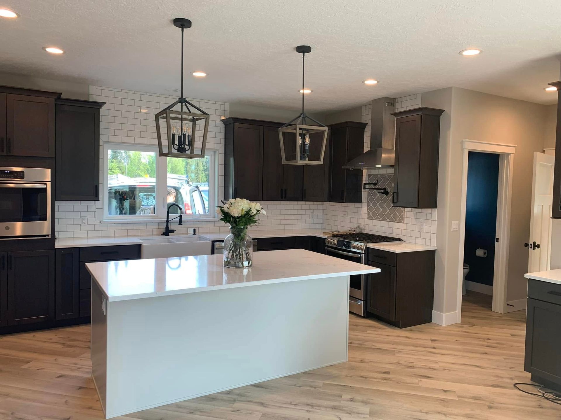 Modern kitchen with white island, dark cabinets, pendant lights, and wood floors
