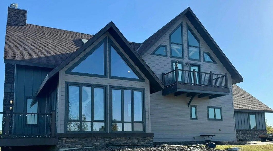 Modern house exterior with steep gabled roof, large windows, and a small balcony by the front entrance