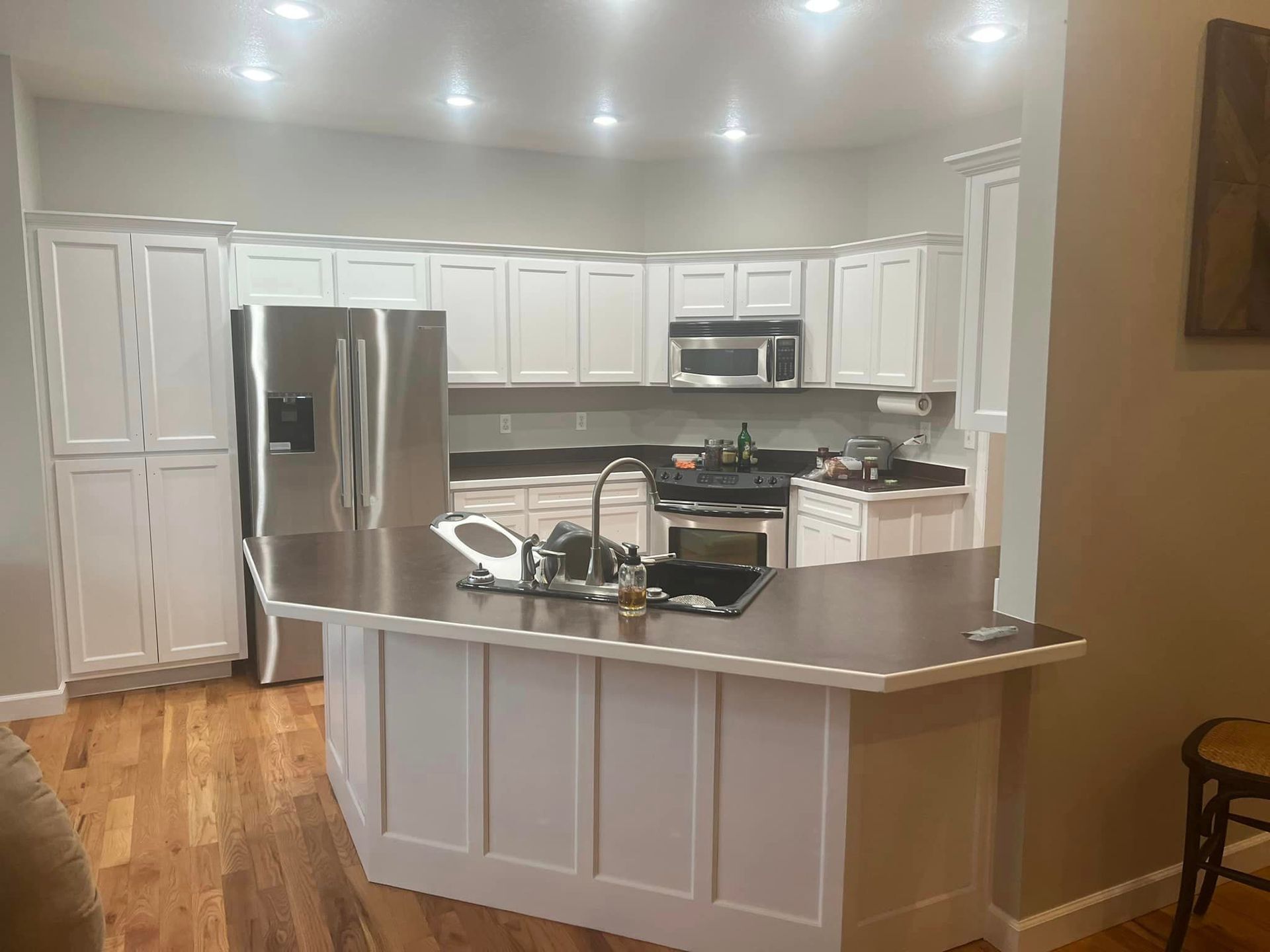 A kitchen with white cabinets, stainless steel appliances, and a dark countertop island.