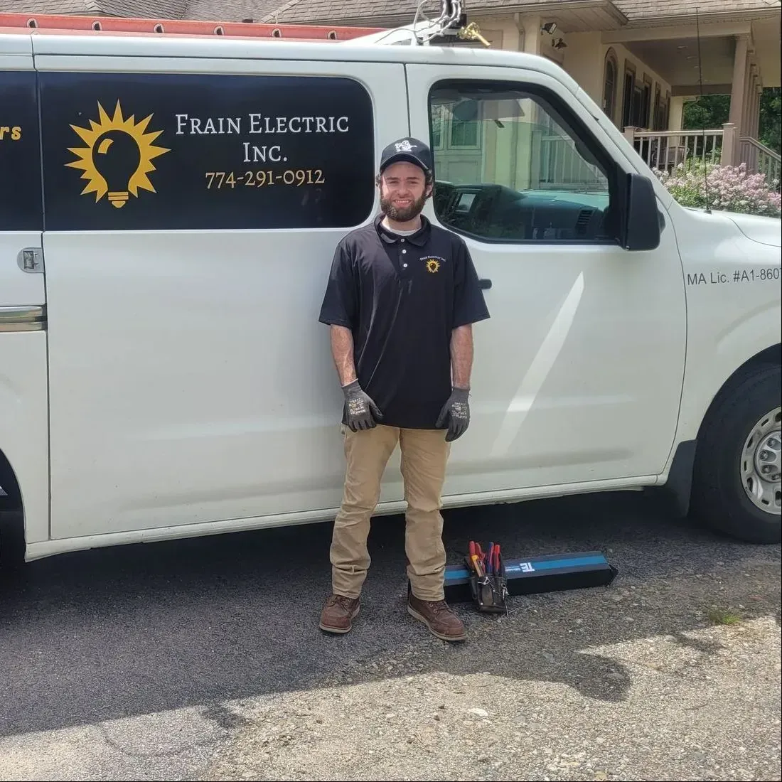 Man in black shirt and tan pants stands next to a white service van with the company logo