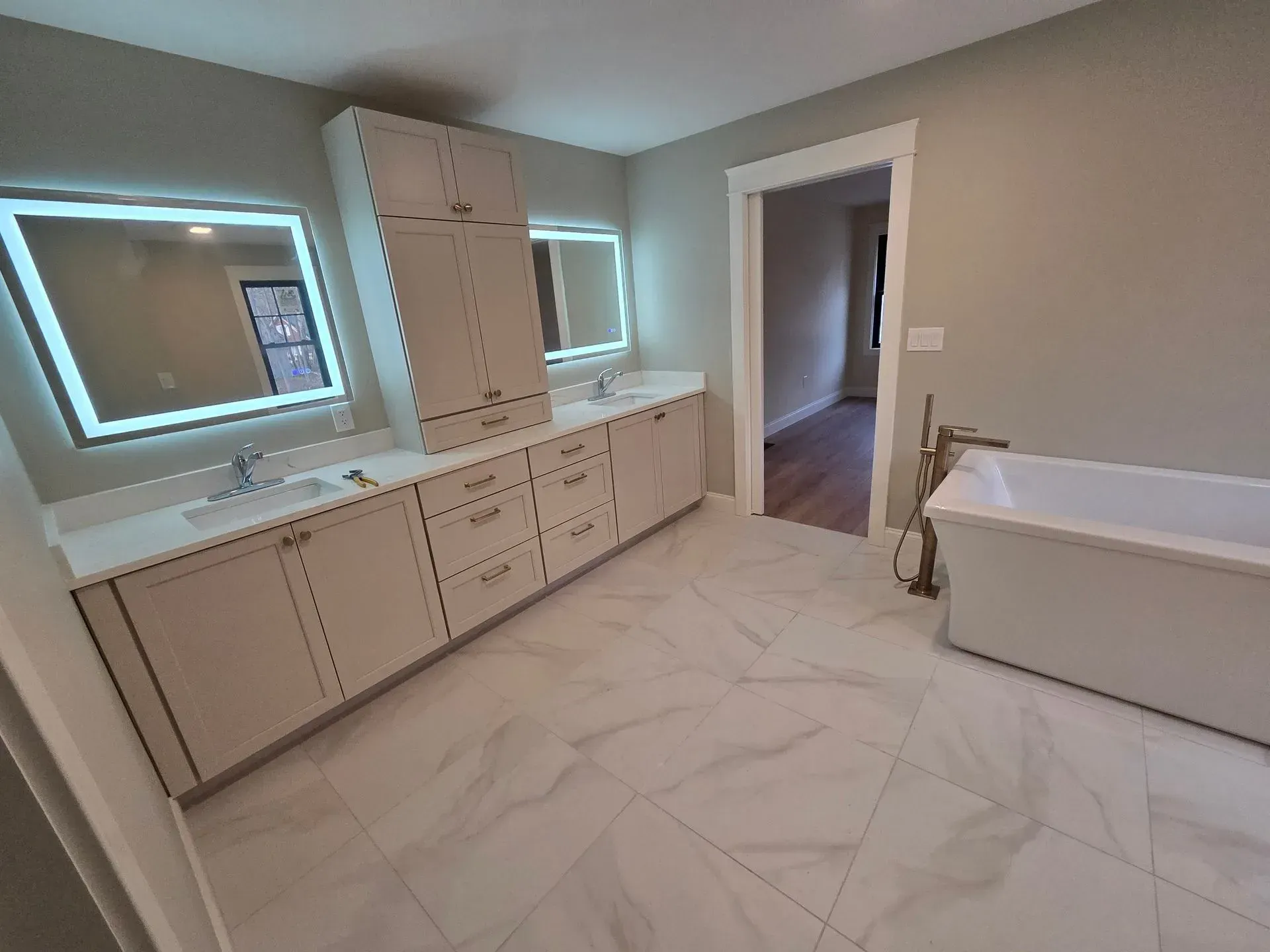 Bathroom with white cabinetry, mirrors, and a freestanding tub.